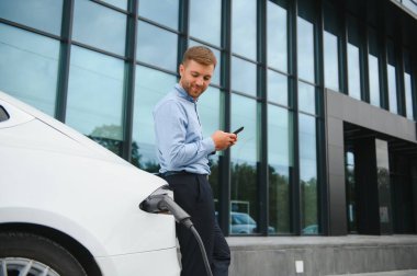 Adam şarj istasyonunda bir elektrikli arabayı şarj ediyor..
