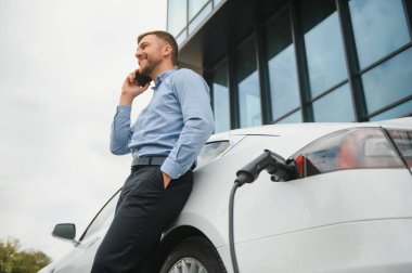 Adam şarj istasyonunda bir elektrikli arabayı şarj ediyor..