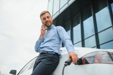 Adam şarj istasyonunda bir elektrikli arabayı şarj ediyor..