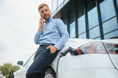 Adam şarj istasyonunda bir elektrikli arabayı şarj ediyor..