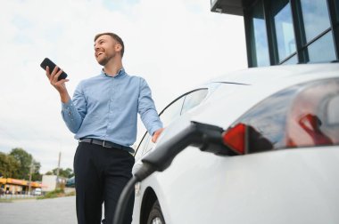 Adam şarj istasyonunda bir elektrikli arabayı şarj ediyor..