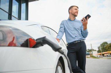 Adam şarj istasyonunda bir elektrikli arabayı şarj ediyor..