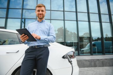 Adam şarj istasyonunda bir elektrikli arabayı şarj ediyor..