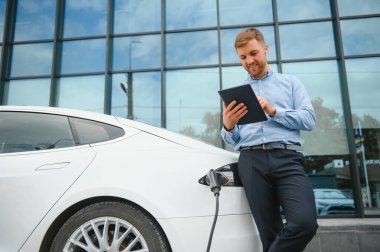 Bir işadamı elektrikli bir arabayı şarj eder