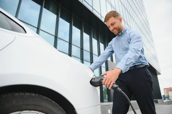 Man charges an electric car at the charging station.