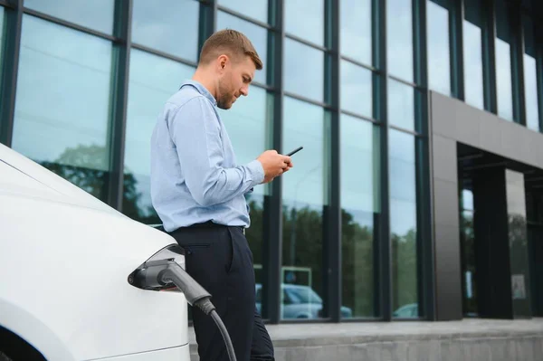 Man charges an electric car at the charging station.