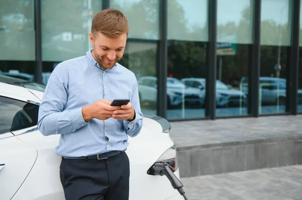 Man Charging His Electric Car Charge Station Using Smartphone — Stockfoto