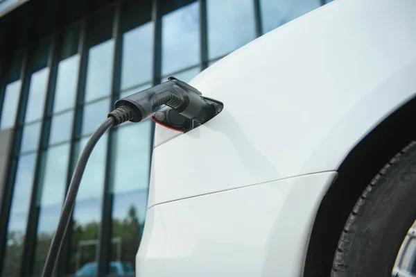 Close up of the Hybrid car electric charger station with power supply plugged into an electric car being charged