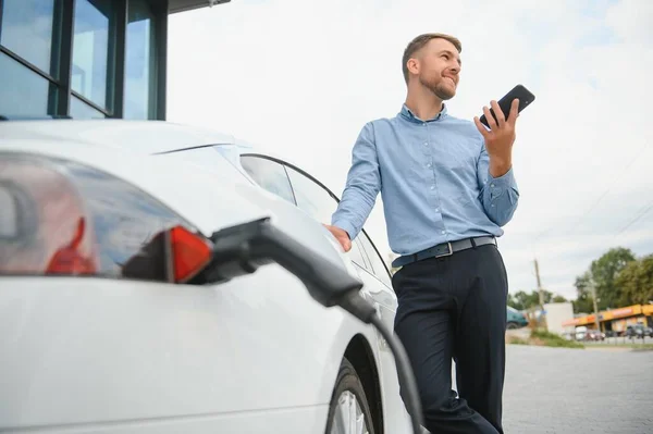 Man charges an electric car at the charging station.