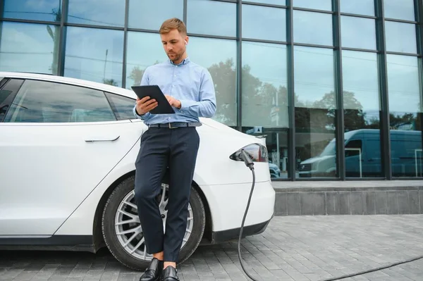 Man charges an electric car at the charging station.