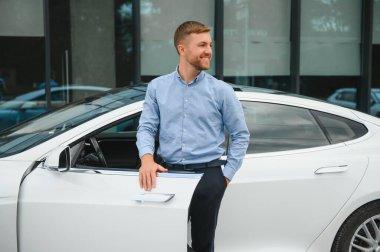 Sokak yolunda modern elektrikli araba kullanırken direksiyon tutan bir iş adamı. Pahalı araba kullanan kendine güvenen bir adam. Sürücü Konforlu Otomobil Seyahatinde Direksiyon Döndürüyor.