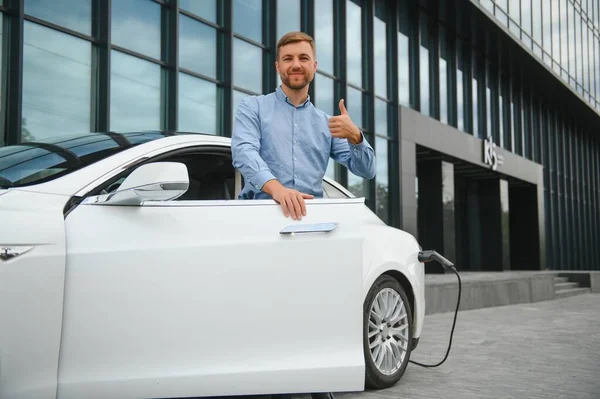 Man charges an electric car at the charging station.