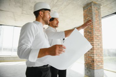 Male Architect Giving Instructions To His Foreman At Construction Site