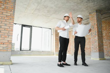 Two young man architect on a building construction site.