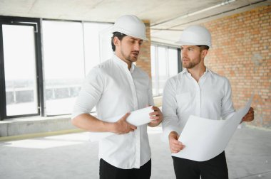 Two young man architect on a building construction site.