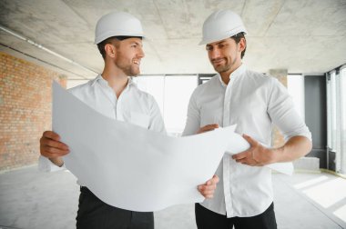 Two young man architect on a building construction site.