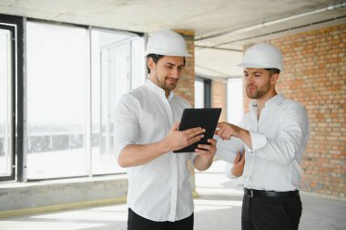 Male Architect Giving Instructions To His Foreman At Construction Site