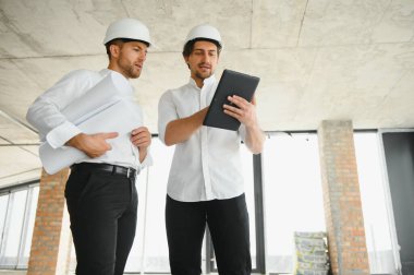 Male Architect Giving Instructions To His Foreman At Construction Site