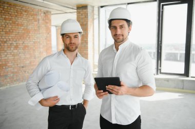 Two young man architect on a building construction site.