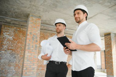 Two young man architect on a building construction site.