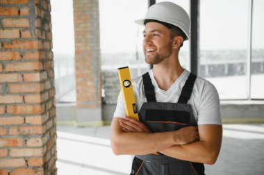 Portrait of handsome male builder in overalls and hard hat.