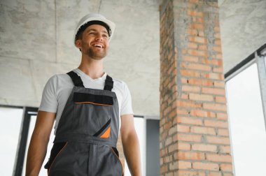 Portrait of handsome male builder in overalls and hard hat.