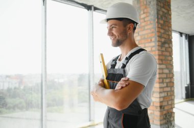 Man builder working in construction site. Male repairer in overall and helmet