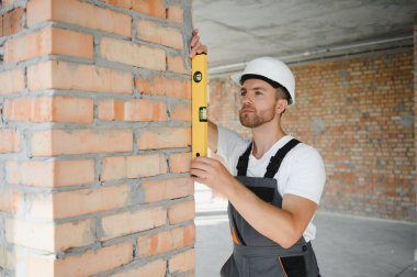 Portrait of handsome male builder in overalls and hard hat.