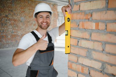 Portrait of handsome male builder in overalls and hard hat.