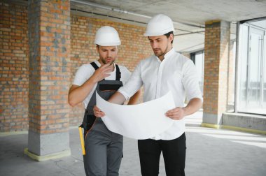 Male Architect Giving Instructions To His Foreman At Construction Site