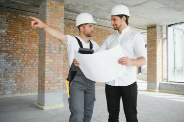 Male Architect Giving Instructions To His Foreman At Construction Site