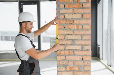 Portrait of handsome male builder in overalls and hard hat.