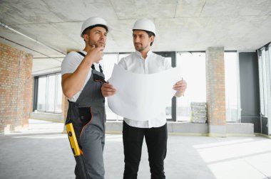 Male Architect Giving Instructions To His Foreman At Construction Site