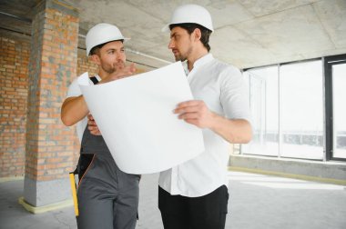 Male Architect Giving Instructions To His Foreman At Construction Site