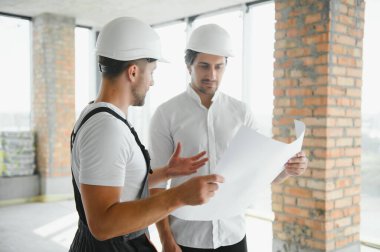 Male Architect Giving Instructions To His Foreman At Construction Site