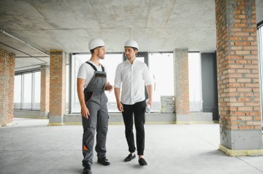 Male Architect Giving Instructions To His Foreman At Construction Site