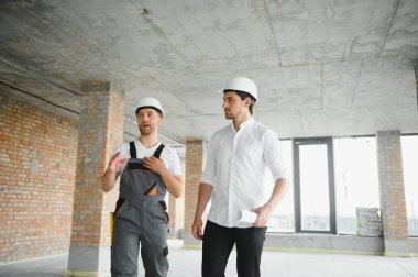 Male Architect Giving Instructions To His Foreman At Construction Site