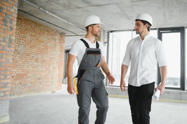 Male Architect Giving Instructions To His Foreman At Construction Site