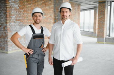 Male Architect Giving Instructions To His Foreman At Construction Site