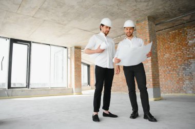 Two young man architect on a building construction site.