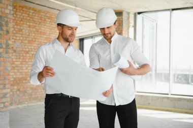 Two young man architect on a building construction site.