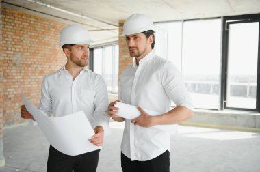 Male Architect Giving Instructions To His Foreman At Construction Site