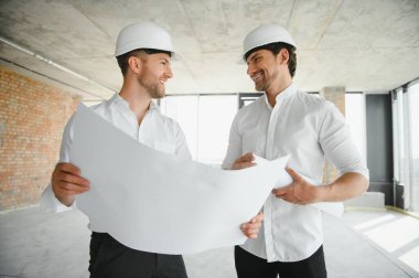Male Architect Giving Instructions To His Foreman At Construction Site