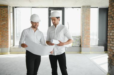 Two young man architect on a building construction site.