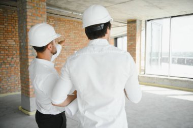 Two young man architect on a building construction site.