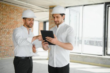 Two young man architect on a building construction site.