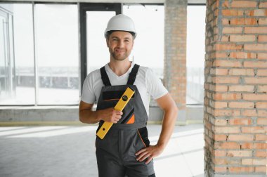 Portrait of handsome male builder in overalls and hard hat.
