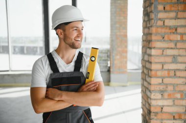 Portrait of handsome male builder in overalls and hard hat.