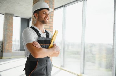 Portrait of handsome male builder in overalls and hard hat.