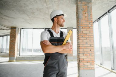 Portrait of handsome male builder in overalls and hard hat.